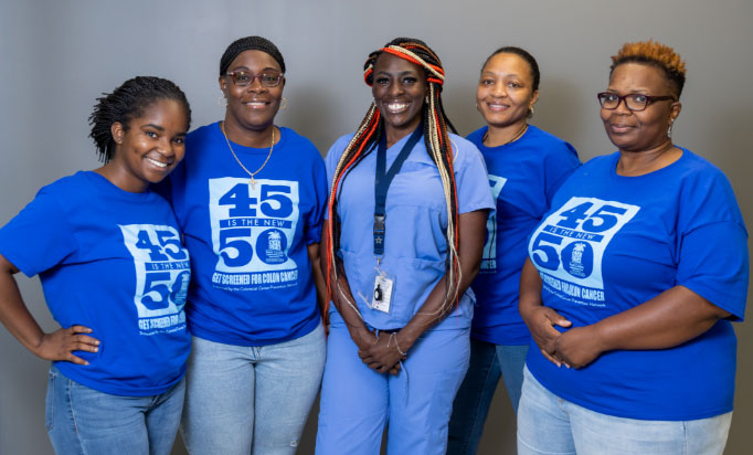 5 women wearing blue shirts standing and smiling 